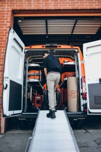 water damage restoration technician rolling equipment out of 911 orange vehicle