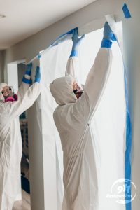 mold removal technicians tape off contaminated room
