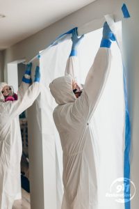 mold removal technicians tape off contaminated room