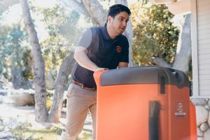 water damage restoration technician pushing equipment into house